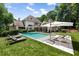 Backyard with a modern swimming pool, lounge chairs, umbrella, and well-manicured lawn surrounded by lush greenery at 1191 W Conway Dr, Atlanta, GA 30327