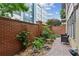 Outdoor patio area surrounded by a brick wall, lush greenery, and paved pathway at 201 W Ponce De Leon Ave # 13, Decatur, GA 30030