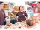Personal at a farmers market behind an extensive display of fresh baked goods at 205 Midnight Oak Run # 5, Alpharetta, GA 30009