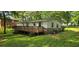 Backyard view featuring a wooden deck, green lawn, and mature trees providing shade at 50 Woodland St, Buford, GA 30518