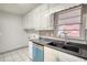 White-tiled kitchen with white cabinets and a stainless steel sink beneath a window at 50 Woodland St, Buford, GA 30518