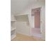 Angled attic walk-in closet with shelving and rod and beige carpet at 828 Jami Ct, Lawrenceville, GA 30046