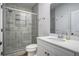 Bathroom featuring grey-tiled shower with glass door and white vanity with solid surface countertop at 953 Mystic Way, Hampton, GA 30228