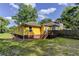 Backyard featuring a yellow house with a deck, green grass, and a vibrant tree line at 103 Chicamauga Sw Ave, Atlanta, GA 30314