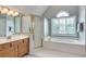 A full bathroom offering a glass shower, soaking tub, and dual sinks with wood cabinets at 3783 Wickford Ln, Peachtree Corners, GA 30096