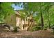 Stucco home's rear exterior with deck, stairs, and surrounded by mature trees at 10660 Dunoon Dr, Alpharetta, GA 30022