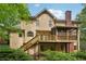 The rear exterior of the home features stairs and a deck overlooking mature greenery at 10660 Dunoon Dr, Alpharetta, GA 30022