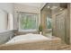 Bright bathroom features a soaking tub, a separate shower with glass door, and a window with a wooded view at 10660 Dunoon Dr, Alpharetta, GA 30022