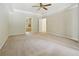 A large bedroom with a tray ceiling, ceiling fan, and windows overlooking the property's landscape at 10660 Dunoon Dr, Alpharetta, GA 30022