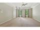 A large bedroom with a tray ceiling, ceiling fan, and windows overlooking the property's landscape at 10660 Dunoon Dr, Alpharetta, GA 30022