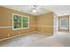 This empty bedroom features tan walls, neutral carpeting, a ceiling fan, and windows with a wooded view at 10660 Dunoon Dr, Alpharetta, GA 30022