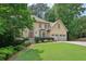 Elegant home showcasing a manicured lawn and a three-car garage, set among mature trees at 10660 Dunoon Dr, Alpharetta, GA 30022