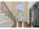 Bright foyer boasts hardwood floors, staircase with iron railing, and chandelier with large windows at 10660 Dunoon Dr, Alpharetta, GA 30022