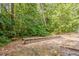 An outdoor space with gravel, a stone wall, and mature trees in the background at 441 Amy Blvd, Temple, GA 30179