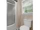 Bathroom with a glass enclosed shower, toilet, and a window with blinds at 9060 Par Dr, Douglasville, GA 30134