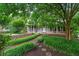 Charming home with a covered front porch, inviting walkway, and lush landscaping with mature trees and flowering plants at 9060 Par Dr, Douglasville, GA 30134