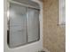 Bathtub with sliding frosted glass door, next to a window with blinds at 9060 Par Dr, Douglasville, GA 30134