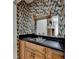 Entertainers wet bar with black countertop and unique wallpaper at 5025 Oak Bluff Ct, Atlanta, GA 30350