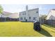 Open backyard boasts a large grassy area, fencing, and back view of the home with a brick chimney at 789 Clairidge Elm Sw Trl, Lawrenceville, GA 30046