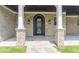 Elegant entrance featuring a decorative wrought iron door, stone pillars, and a stone walkway at 140 Maranatha Trl, Lawrenceville, GA 30045