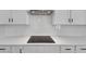 Modern kitchen featuring white cabinets, white tile backsplash, and a smooth cooktop on the counter at 212 Birchwood Row, Canton, GA 30115