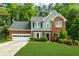 Two-story home with manicured lawn, brick accents, and attached garage surrounded by mature trees at 2865 Ivey Oaks Ln, Roswell, GA 30076