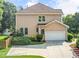Side view of a tan home with a two car garage and a nice, green lawn at 2810 Promenade Pl, Buford, GA 30519