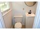 Cozy bathroom with a toilet, vanity with cabinet, black faucet, and a round mirror above at 579 Kenridge Cir, Stone Mountain, GA 30083