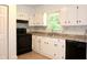 Well-appointed kitchen featuring white cabinets, laminate countertops, and black appliances beneath a bright window at 579 Kenridge Cir, Stone Mountain, GA 30083