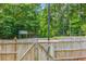 Spacious backyard featuring a wooden privacy fence, mature trees, and a charming ' playhouse for outdoor fun at 65 Millennial Ct, Lawrenceville, GA 30045