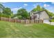 Large, fenced backyard with lush green lawn, mature trees, and a two-story home with a private deck at 65 Millennial Ct, Lawrenceville, GA 30045