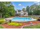 Private backyard oasis with a sparkling pool, mature trees, lush landscaping, and an inviting patio for relaxation at 65 Millennial Ct, Lawrenceville, GA 30045