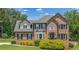 Charming two-story brick home with manicured lawn and mature landscaping, set against a backdrop of lush trees at 65 Millennial Ct, Lawrenceville, GA 30045