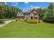 Expansive green lawn surrounds a classic two-story brick home with black shutters and well-maintained landscaping at 65 Millennial Ct, Lawrenceville, GA 30045