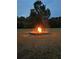Backyard fire pit area with a glowing bonfire and a backdrop of trees under a clear sky at 2997 Happy Hollow Se Dr, Conyers, GA 30094