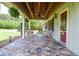 Charming covered porch with stone flooring, wicker chairs, and view of the landscaped yard at 2997 Happy Hollow Se Dr, Conyers, GA 30094