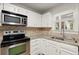 Well-lit kitchen featuring stainless steel appliances, granite countertops, and updated white cabinets at 403 Abingdon Way, Atlanta, GA 30328