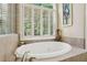 Elegant bathroom featuring a soaking tub surrounded by large windows, offering a spa-like ambiance at 503 Kensington Estates Trce, Woodstock, GA 30188