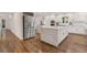 Open concept kitchen with stainless steel fridge, double islands, bright white cabinets, and hardwood flooring at 2655 Boulder Creek Ne Dr, Roswell, GA 30075