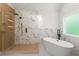 Bright bathroom with a glass-enclosed shower with wood tile accents and a freestanding bathtub with a modern black faucet at 5150 Shadow Path Sw Ln, Lilburn, GA 30047