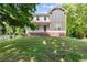Rear view of a spacious home featuring a lush lawn, a side-entry garage, and mature trees at 5150 Shadow Path Sw Ln, Lilburn, GA 30047