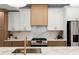 Modern kitchen featuring white and brown cabinets, stainless steel appliances, and a beautiful marble backsplash at 5150 Shadow Path Sw Ln, Lilburn, GA 30047