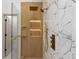 Close-up of a stylish shower with wood-look tile accents, glass enclosure and gold fixtures at 5150 Shadow Path Sw Ln, Lilburn, GA 30047