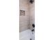 Close up of bath tub with sleek gray wall tiles, a recessed shelf, and a modern shower head at 1029 Katherwood Sw Dr, Atlanta, GA 30310