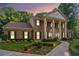 Charming brick home featuring a columned entryway, manicured lawn, and lush landscaping at 2080 Old Dominion Rd, Atlanta, GA 30350