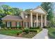 Charming brick home featuring a columned entryway, manicured lawn, and lush landscaping at 2080 Old Dominion Rd, Atlanta, GA 30350