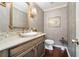 Elegant powder room featuring a wooden vanity, stylish wallpaper, and a gold-framed mirror for a luxurious touch at 2080 Old Dominion Rd, Atlanta, GA 30350