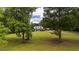 White farmhouse situated on a grassy lot with mature trees providing shade and privacy at 253 Pine Valley Dr, Powder Springs, GA 30127
