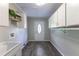 Well-lit laundry room with gray flooring, white walls, storage cabinets, and an exterior door at 253 Pine Valley Dr, Powder Springs, GA 30127