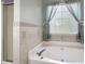 Bathroom with tile, shower, a corner tub, and decorative curtains over a window at 3573 Bramwell Nw Xing, Kennesaw, GA 30144